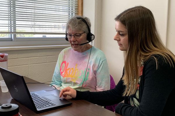 Student clinician working with client on creating speech and voice recordings using a laptop.