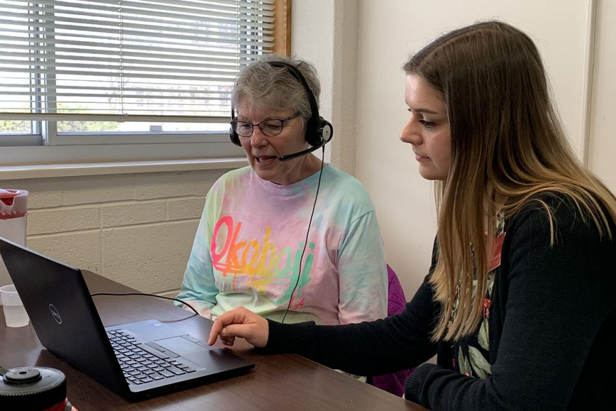 Student clinician working with client on creating speech and voice recordings using a laptop.