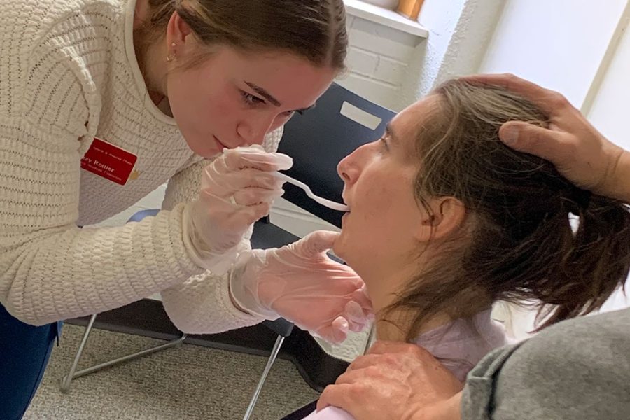 Graduate student clinician completing liquid trials with a client working on swallowing.