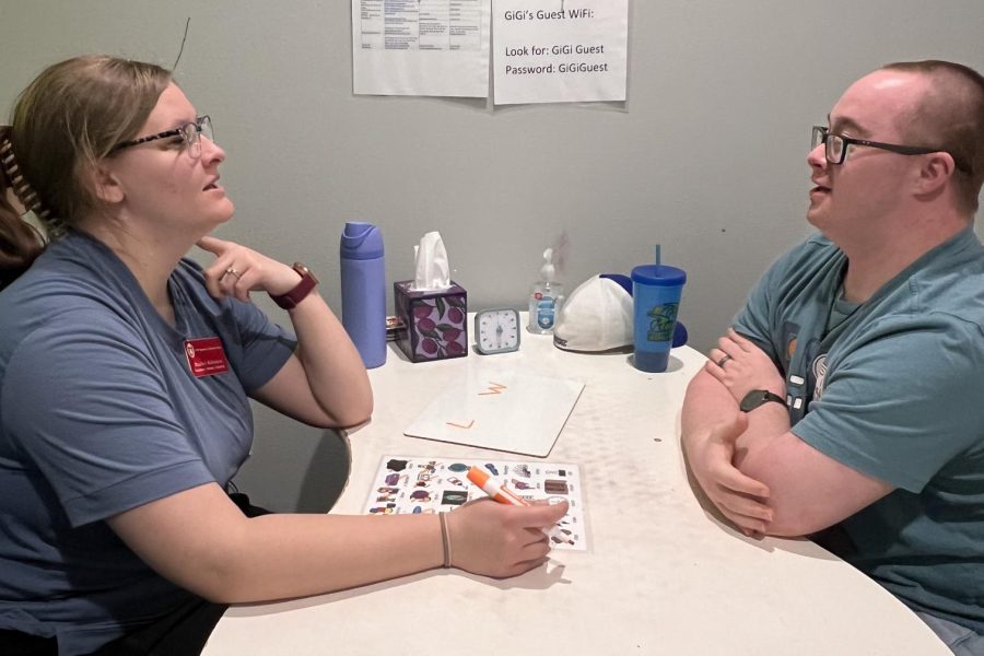 A graduate student clinician working with an adult client in a speech-language therapy session.