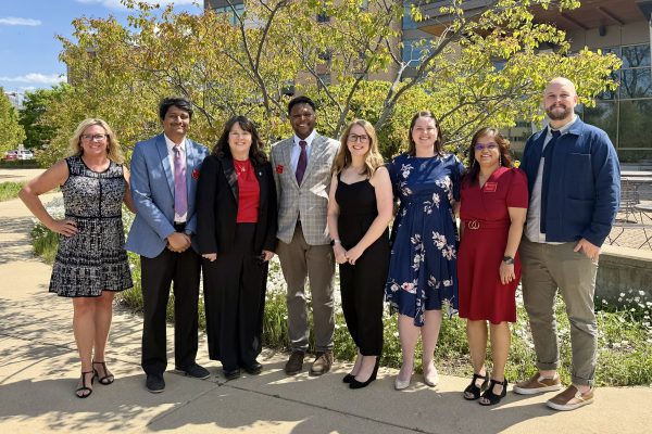 Audiology clinical and academic faculty, from left to right, Amy Kroll, Nike Gnanateja, Amy Hartman, Bobby Gibbs, Rachel Lee, Margaret Koeritzer, Dhatri Devaraju, and Erik Jorgensen outside the Doctor of Audiology department graduation ceremony at Dejope residence hall on a warm spring day at the University of Wisconsin-Madison on May 8, 2026.
