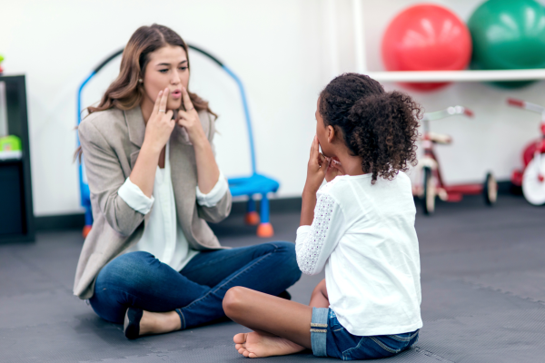 A speech pathologist works with a child on speech sound production skills.