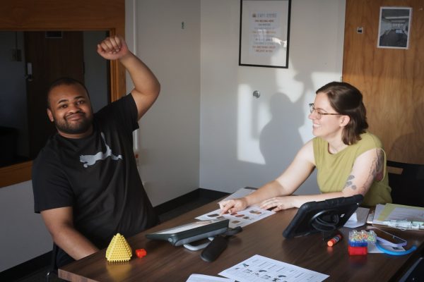 A speech-language pathology graduate student works with a client and their AAC device.