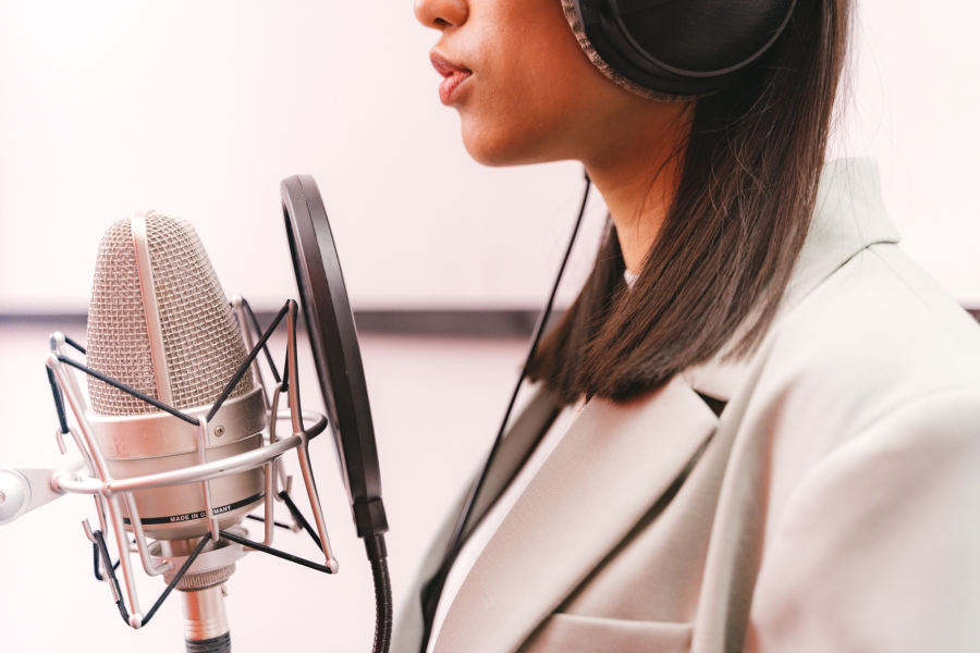 A woman is shown close up next to a large microphone.