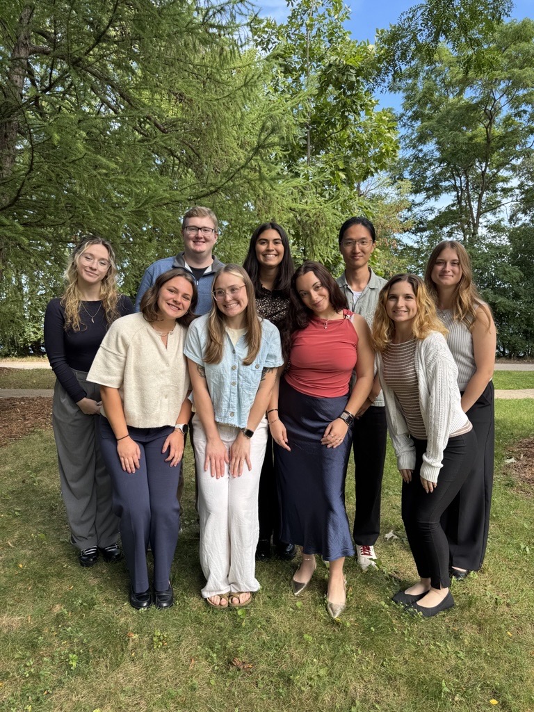Group of first year audiology graduate students gathered together outside of Goodnight Hall, with Lake Mendota in the background.