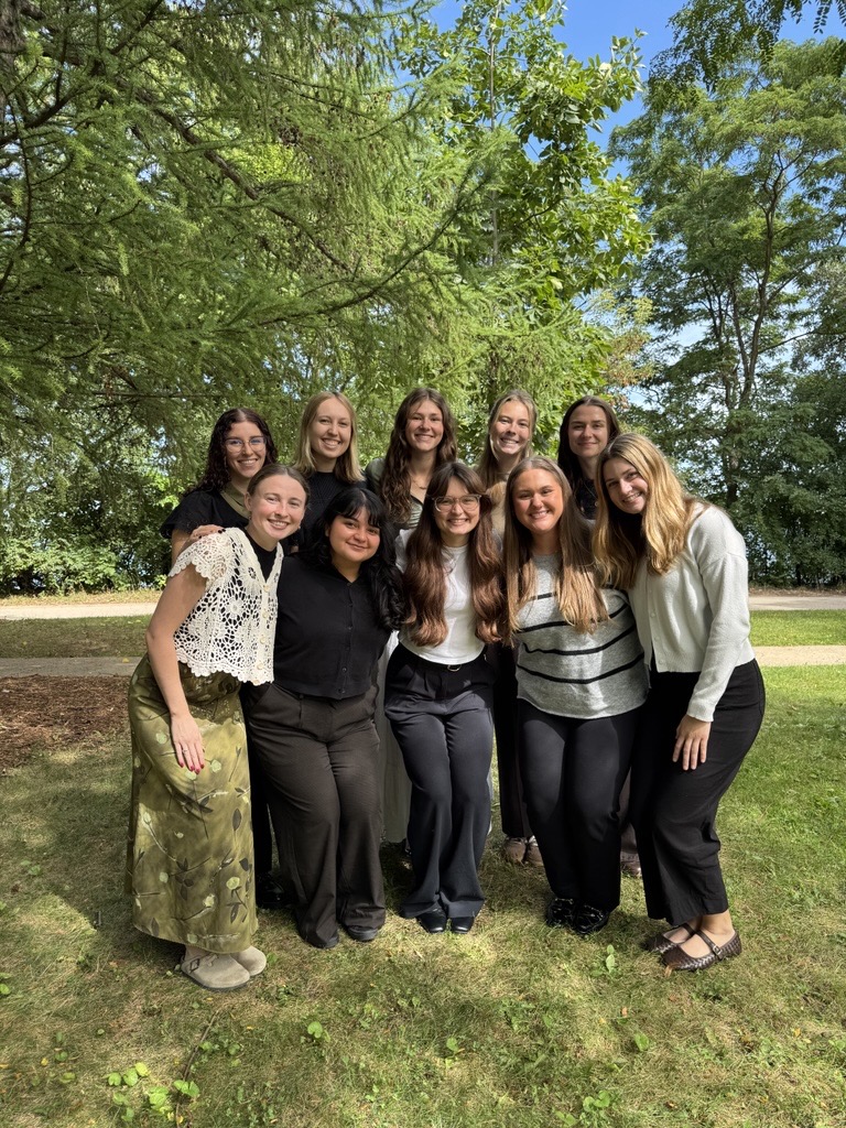 Group of second year audiology graduate students gathered together outside of Goodnight Hall, with Lake Mendota in the background.